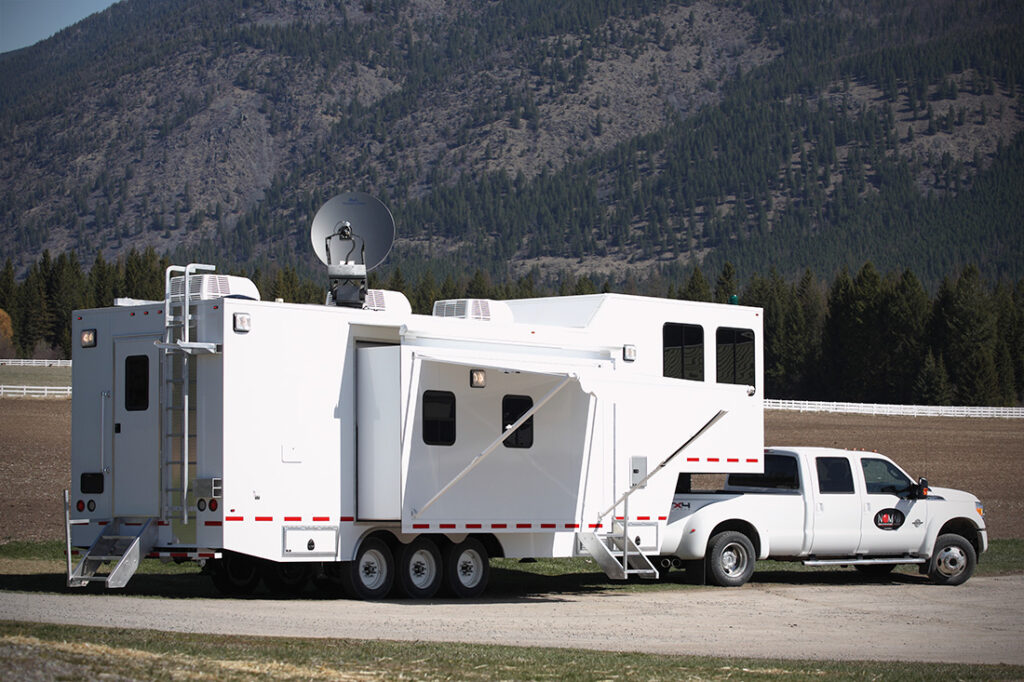 Rear of trailer with deployed satellite, curb side slideout and awning.